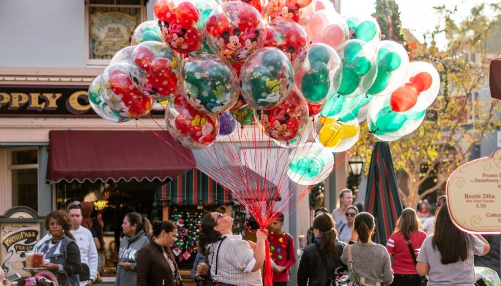 A person selling colorful balloons with cartoon characters at a bustling outdoor market or amusement park.