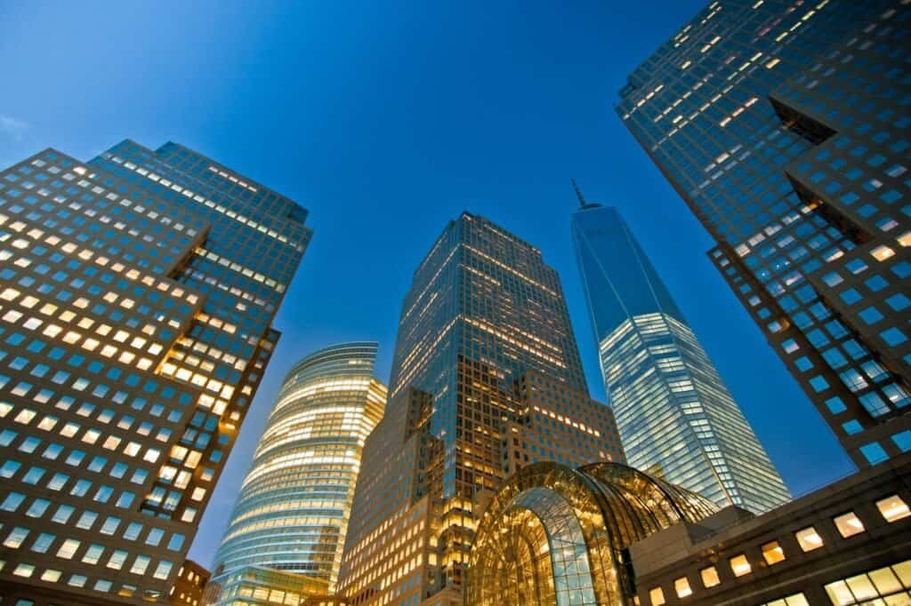 Tall modern skyscrapers with illuminated windows pierce the clear evening sky, creating a stunning urban vista that could well be featured in any destination guide.