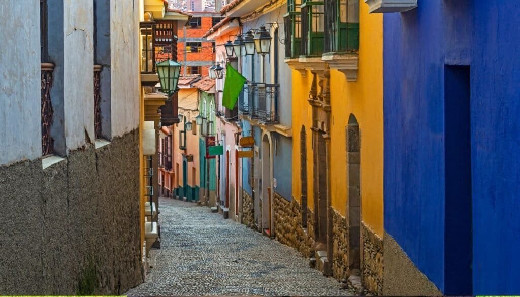 Narrow cobblestone street lined with colorful buildings featuring balconies and streetlamps, a perfect scene for budget travel lovers seeking charm without breaking the bank.