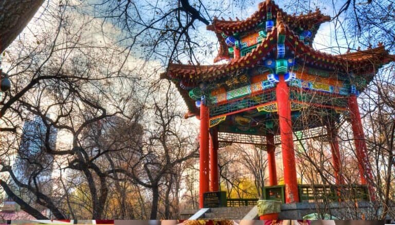 A traditional pagoda with ornate detailing stands amidst bare trees, under a partly cloudy sky. Cultural Travel