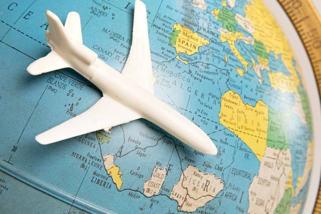 A small white model airplane is positioned on a globe, with parts of Europe and Africa visible underneath.