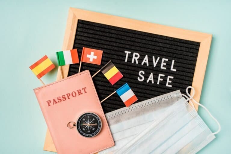A felt board reads "Travel Safe," encircled by a passport, compass, and face masks alongside miniature flags of Germany, Italy, Switzerland, Belgium, and France. Discover essential travel safety tips to ensure your adventures across these countries are both exciting and secure.