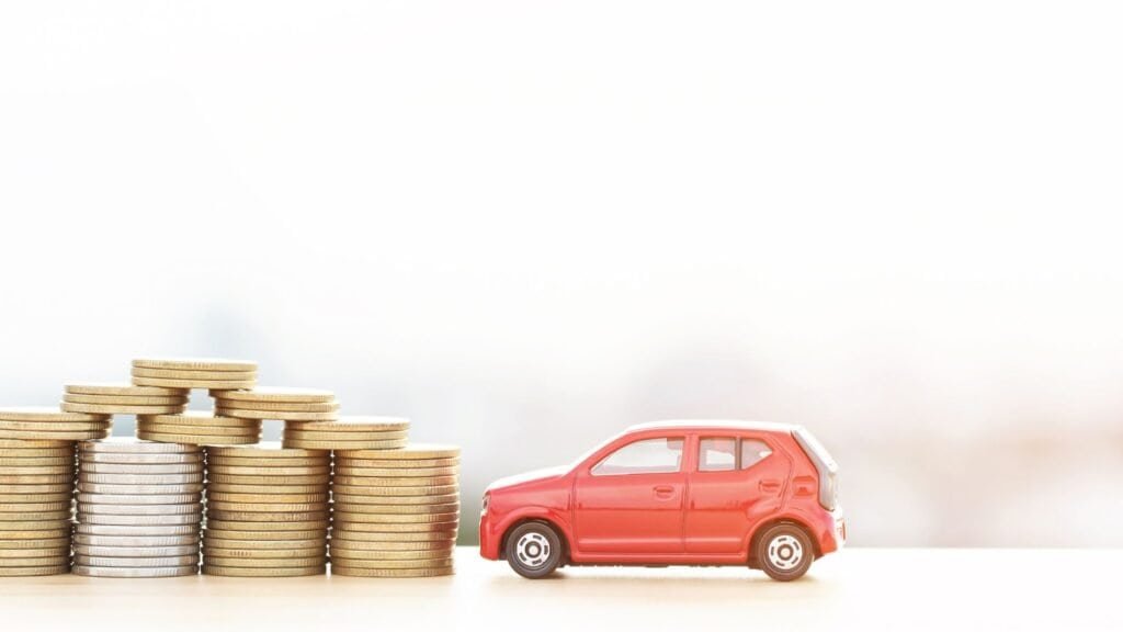 A small red toy car, symbolizing efficient family travel hacks, is parked next to several stacks of gold coins on a light background.